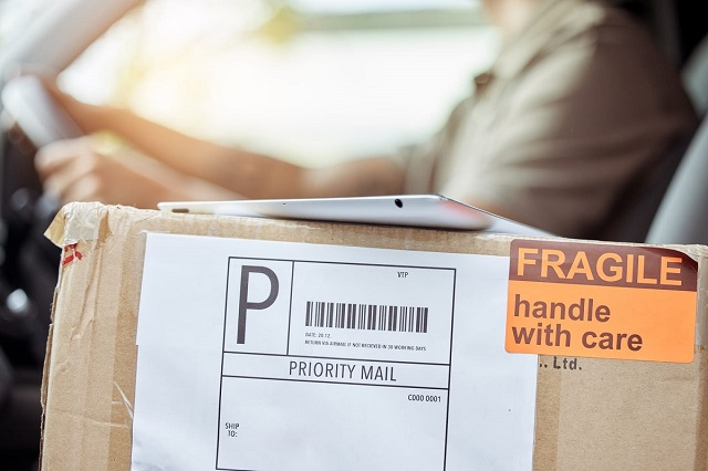 Closeup of a package with a shipping label with a tablet sitting on top