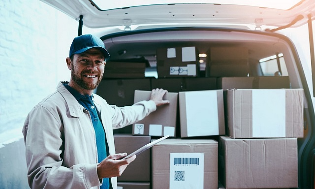 Delivery driver removing packages from the back of a delivery van