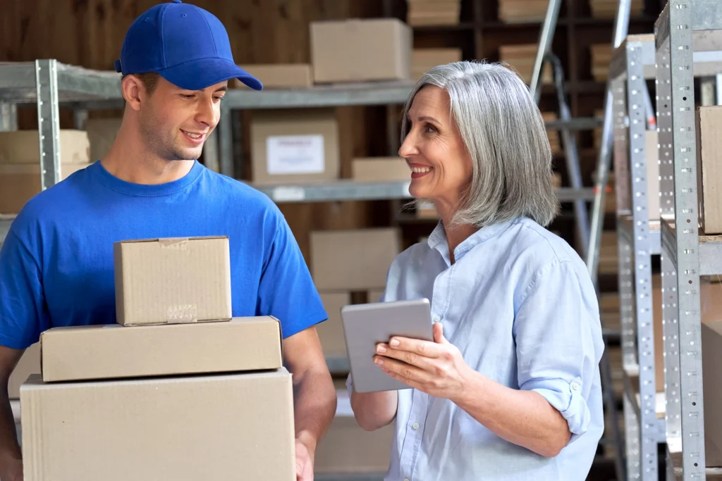 Warehouse manager talking to delivery professional who is carrying packages