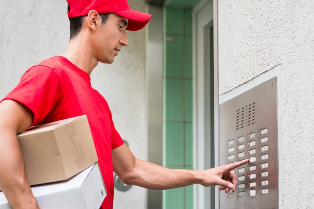 Delivery professional pressing intercom button to enter an apartment building