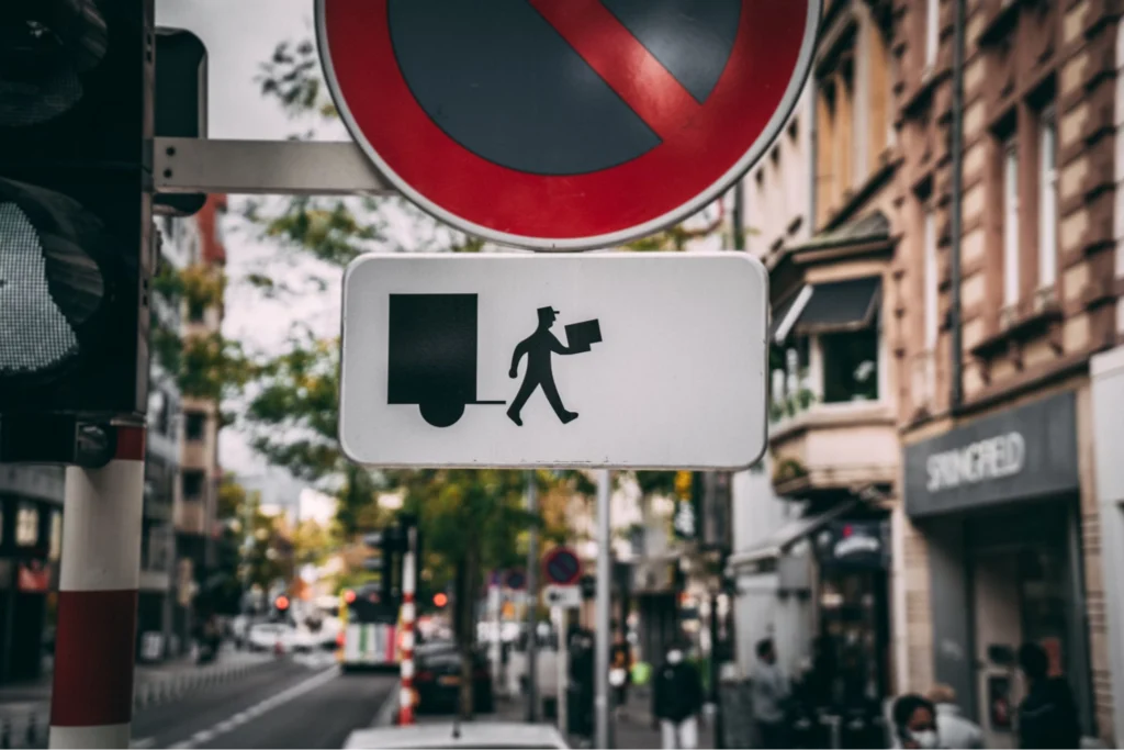 Delivery person crossing sign on a busy street