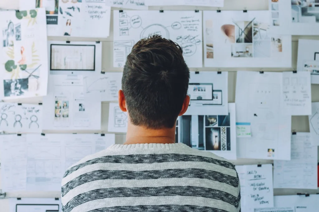 Person reviewing strategic planning diagrams and notes on a wall 